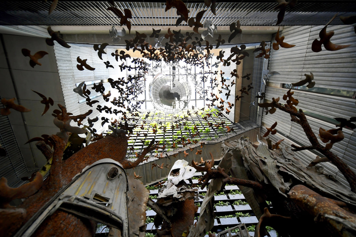 Art installation featuring white doves and green branches rising from wreckage of a warplane, symbolizing peace and reconciliation